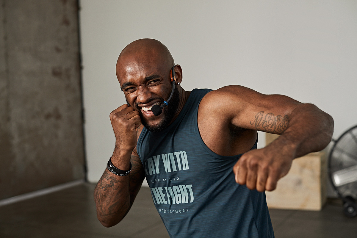 A fitness instructor wearing a headset demonstrates a punch during a high-energy workout class.