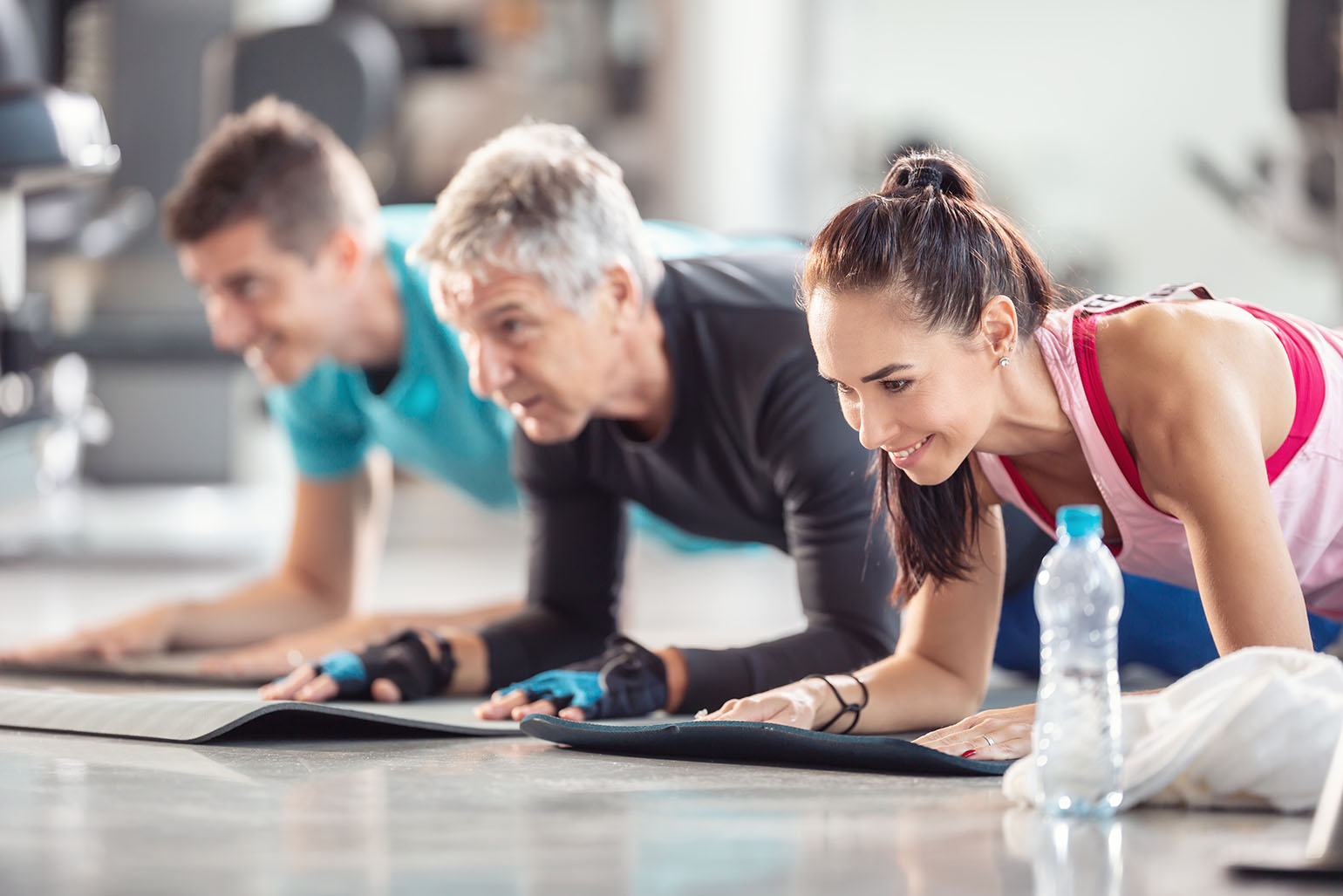 Group of people in a fitness class holding plank positions on yoga mats indoors. Group of people in a fitness class holding plank positions on yoga mats indoors.